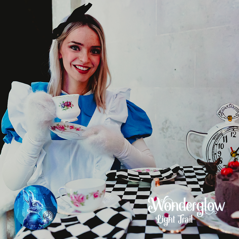 Image of Alice from Alice In Wonderland sat in her blue and white dress holding a tea cup